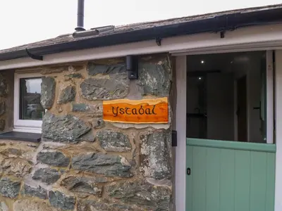 a uschool sign on a stone wall next to a garage at Y Stabl in Dyffryn