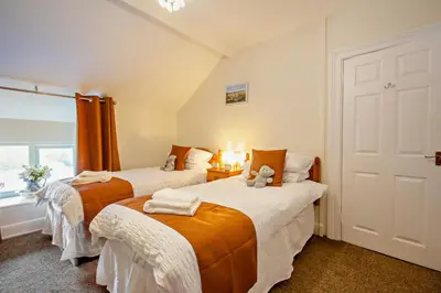 two beds in a room with a teddy bear sitting on top at 3 Bed in Llanbedr oc-t28932 in Llanbedr
