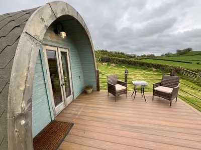 a wooden deck with chairs and a table on a building at The Pod Patch - Bryn Pod in Bishops Castle