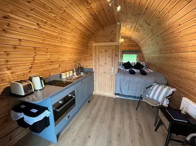 a room with a bed and a kitchen in a cabin at The Pod Patch - Bryn Pod in Bishops Castle