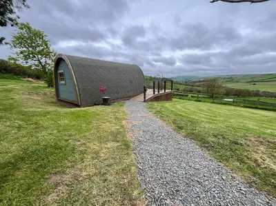 a small building with a roof on a grass field at The Pod Patch - Bryn Pod in Bishops Castle