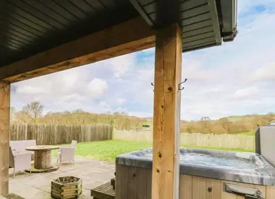 a patio with a hot tub and a table at Caban Dulas in Nantmel