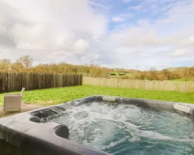 a hot tub in a yard with a fence at Caban Dulas in Nantmel