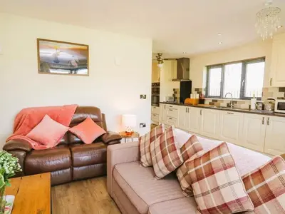 a living room with a leather couch and a kitchen at Caban Dulas in Nantmel