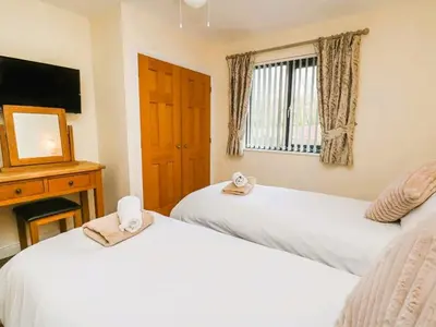 a bedroom with two beds and a mirror and a window at Caban Dulas in Nantmel