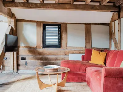 a living room with a red couch and a table at Hayloft Barn in Clifford