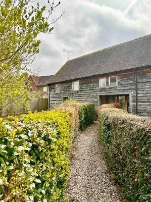 a house with hedges in front of a building at Serafina Cottage in Leominster