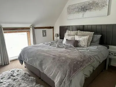 a bedroom with a bed with a gray comforter and a window at Serafina Cottage in Leominster