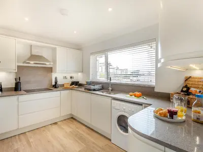a kitchen with white cabinets and a dishwasher at Goppa in Llanfair