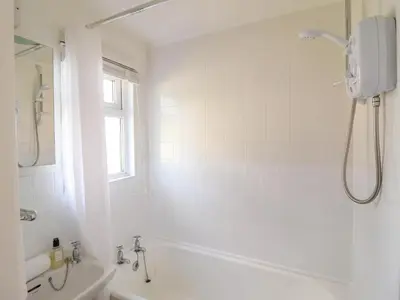 a bathroom with a shower and a tub and a sink at Hill View in Tywyn