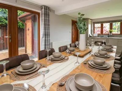 a dining room with a long table and chairs at Pondarosa in Llandrindod Wells