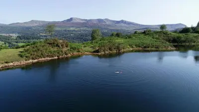 a boat in the middle of a large lake at Swn y nant Barmouth road A496 Llanelltyd in Penmaenpool