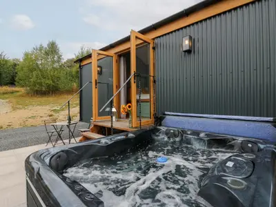 a hot tub in front of a tiny house at Dam View Shepherds Hut in Rhayader