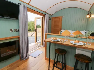 a kitchen with a bar and a fireplace in a room at Dam View Shepherds Hut in Rhayader