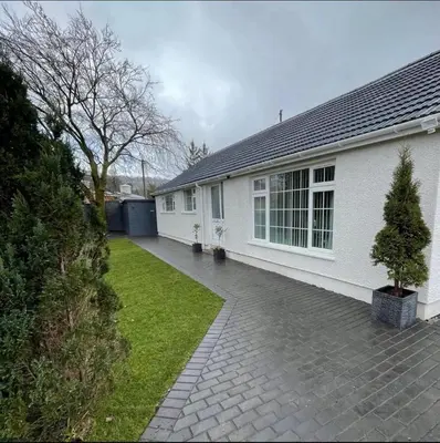 a white house with a driveway next to a yard at Birch Villa in Aberystwyth