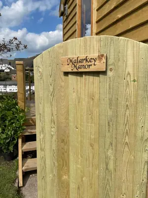 a wooden sign on the side of a wooden fence at Stylish Shepherds Hut with Amazing Views in Knighton