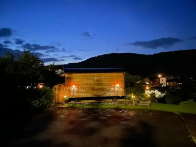 a wooden building with lights on it at night at Stylish Shepherds Hut with Amazing Views in Knighton