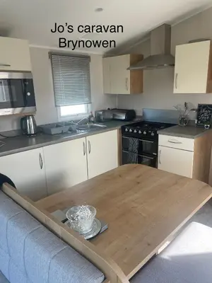 a kitchen with a wooden table in the middle at Caravan by the beach in Borth