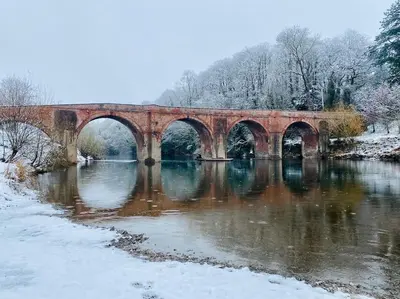 a bridge over a river with snow on the ground at The Guest House near Hay on Wye in Hereford