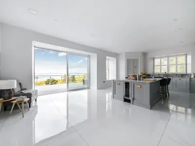 a kitchen with white tile flooring and a large window at Plas Amherst in Harlech