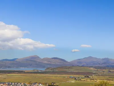a view of a field with mountains and a body of water at Valerian Lodge in Harlech