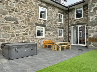 a patio with a grill and a table and a bench at Valerian Lodge in Harlech