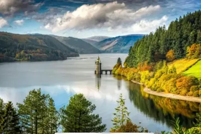 a lake in the mountains with a dock in the water at Tank Barn at Brook House, Nestled in the Welsh Hills, a delightful retreat in Welshpool