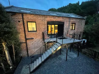 a brick house with a balcony and a building at Tank Barn at Brook House, Nestled in the Welsh Hills, a delightful retreat in Welshpool
