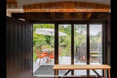 a patio with a table and an umbrella at Tank Barn at Brook House, Nestled in the Welsh Hills, a delightful retreat in Welshpool