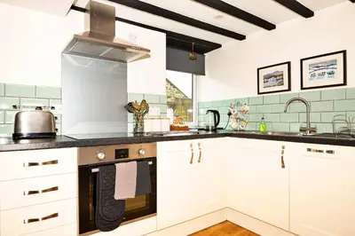 a kitchen with white cabinets and a stove top oven at Finest Retreats - Hermon Bach in Dolgellau
