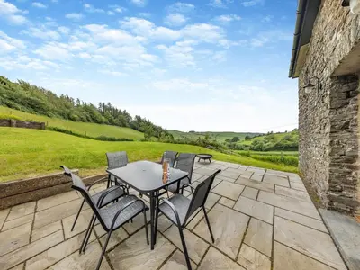 a table and chairs on a patio with a view at Ty Carreg in Llanbadarn-fawr