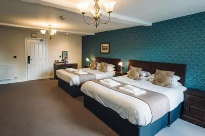 two beds in a hotel room with blue walls at White Lion Royal Hotel in Bala