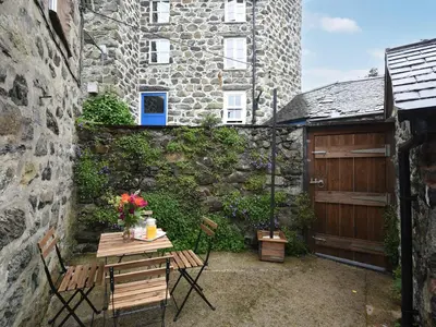 a patio with a table and chairs and a building at Llys Dedwydd in Dolgellau