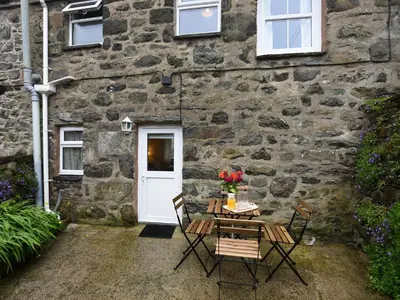 a table and chairs in front of a stone house at Llys Dedwydd in Dolgellau