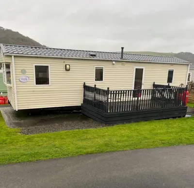 a mobile home with a porch and a fence at Discover Serenity in Our 3-Bed Static Caravan at Clarach Bay Holiday Village! in Aberystwyth