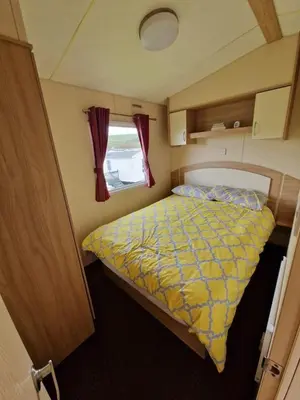 a small bedroom with a bed and a window at Discover Serenity in Our 3-Bed Static Caravan at Clarach Bay Holiday Village! in Aberystwyth
