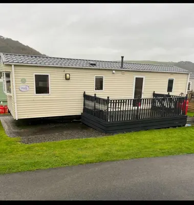 a mobile home with a porch and a fence at Discover Serenity in Our 3-Bed Static Caravan at Clarach Bay Holiday Village! in Aberystwyth