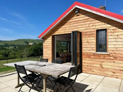 a wooden cabin with a table in front of it at The Bw thyn - Ceredigion in Lampeter