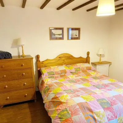 a bedroom with a bed and a dresser at Llynhillyn Cottage in Presteigne