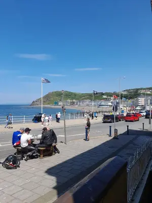 a group of people sitting on a bench near the beach at Harley's in Aberystwyth
