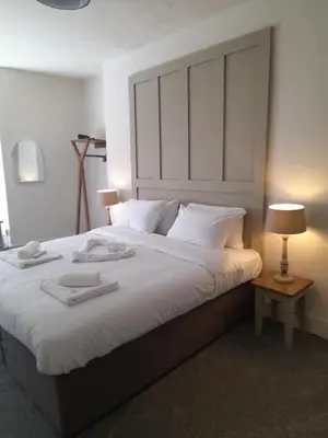 a bedroom with a large bed with towels on it at Harley's in Aberystwyth