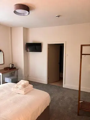 a hotel room with a bed and a television on the wall at Harley's in Aberystwyth