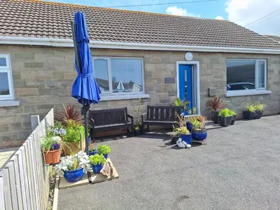 a blue umbrella in front of a house with potted plants at Brynarfor near Aberaeron in Llanon