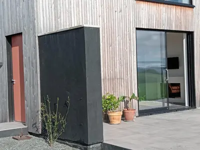 a building with glass doors and potted plants on the side at The Slow House Apartments, Llandefalle in Brecon