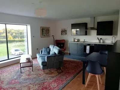 a living room with a blue couch and a kitchen at The Slow House Apartments, Llandefalle in Brecon
