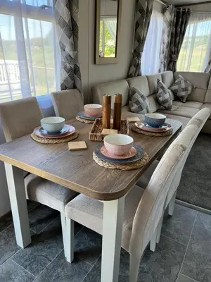 a dining room table with chairs and a couch at Visma Caravan in Llanddwywe