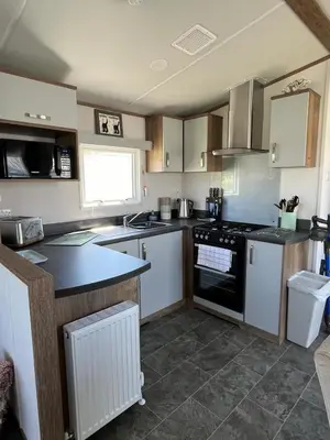 a kitchen with white cabinets and a stove top oven at Visma Caravan in Llanddwywe