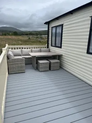 a patio with a couch and a table on a building at Visma Caravan in Llanddwywe