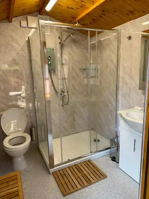 a bathroom with a shower with a toilet and a sink at Cwt Bugail Aeron in Aberaeron