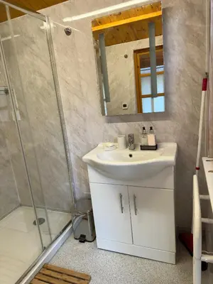 a bathroom with a white sink and a shower at Cwt Bugail Aeron in Aberaeron